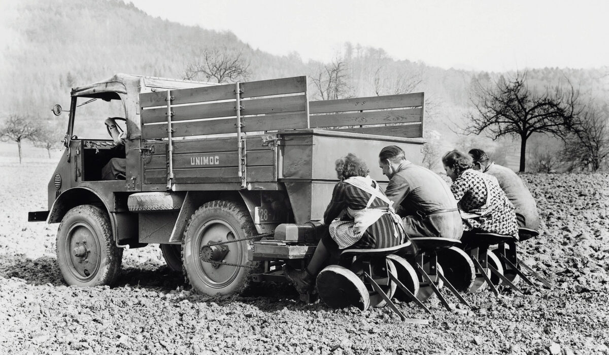 Erntehelfer mit 25 PS: Die halbautomatische Kartoffel-Pflanzmaschine war ein Anbaugerät aus den Anfangsjahren des Unimog. Die Spurbreite des Unimog war auf die Kartoffelreihen ausgelegt: 1270 mm betrug sie und so passten zwei Kartoffelreihen genau zwischen die Räder
A farmhand with 25 hp: the semi-automatic potato planting machine was an implement dating back to the beginnings of the Unimog. The track width of the Unimog was designed for work amongst the potato rows: it was 1270 mm which was sufficient space for precisely two rows of potatoes between the wheels.